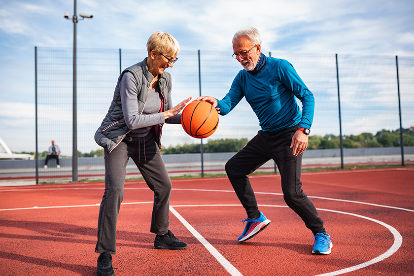 Senior couple playing basketball outdoors 